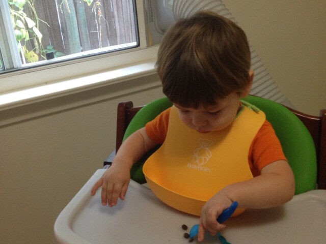 Working on using a fork to eat his beans